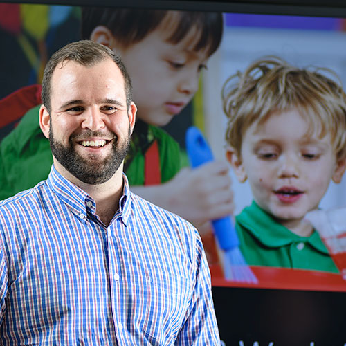 Kevin Clare English for Asia TESOL trainer standing in front of an image of young learers