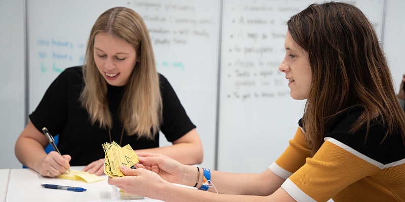 Two teacher trainers preparing a lesson in a classroom.